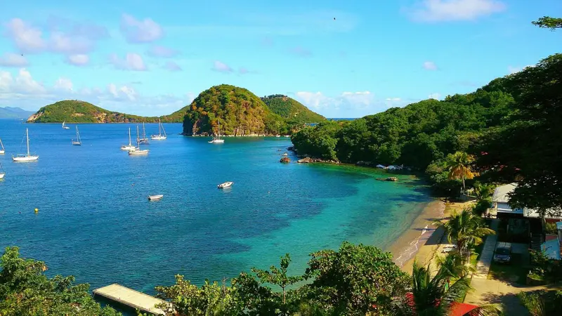 Vue panoramique sur une baie turquoise bordée de végétation et de plages.