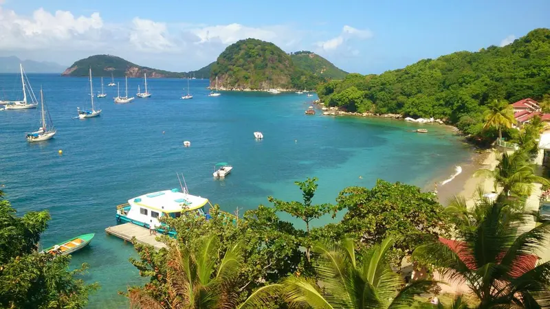 Vue aérienne d'une baie abritée avec des bateaux à voile et une plage.