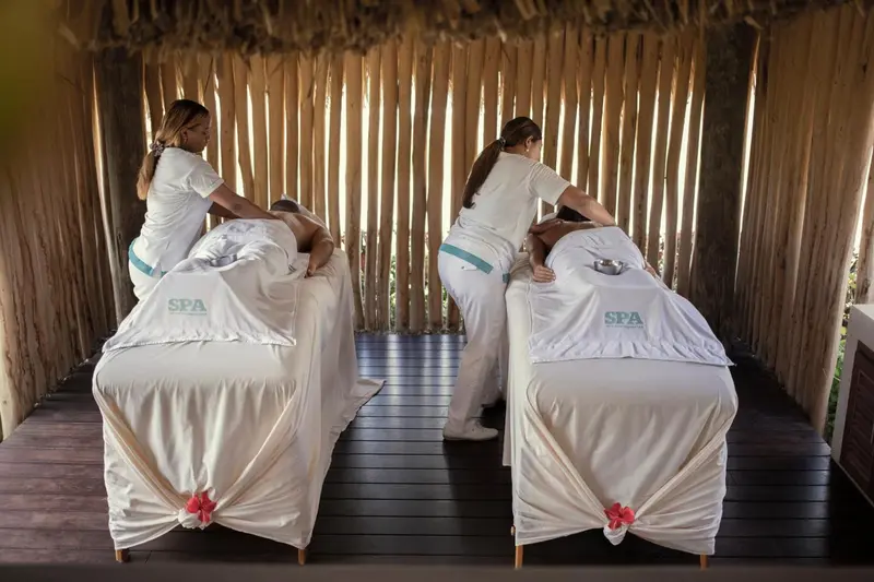 Trois personnes allongées sur des tables de massage dans un espace ouvert et lumineux.