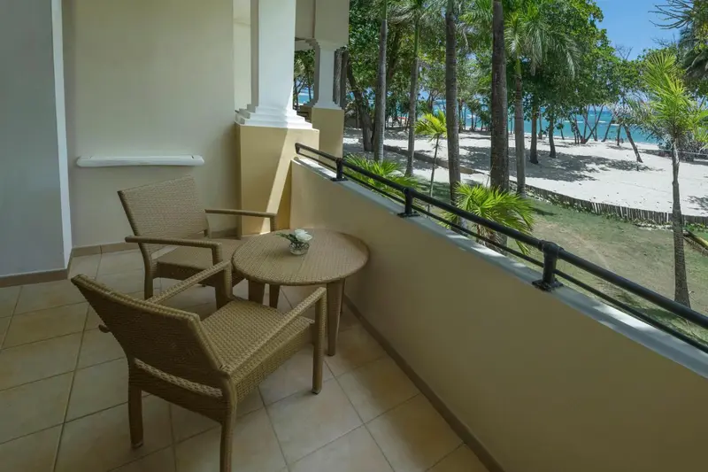 Terrasse avec mobilier en rotin donnant sur une plage de sable fin et la mer.