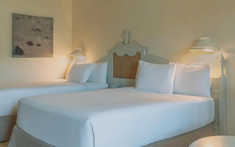 Une chambre lumineuse avec deux lits simples et une décoration murale.