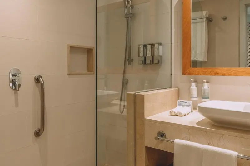 Une douche à l'italienne avec des produits de toilette et un lavabo.
