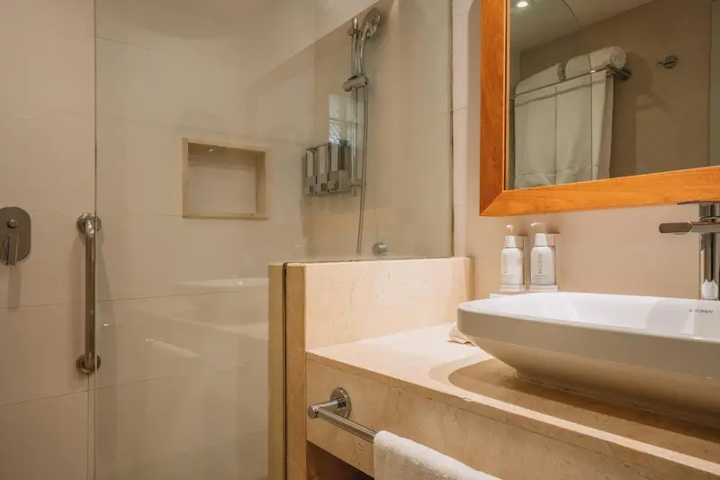 Une salle de bain claire avec douche à l'italienne et vasque.