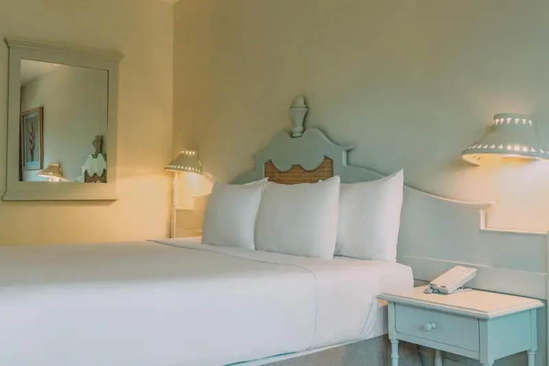 Une chambre lumineuse avec un lit recouvert de draps blancs et une table de chevet.