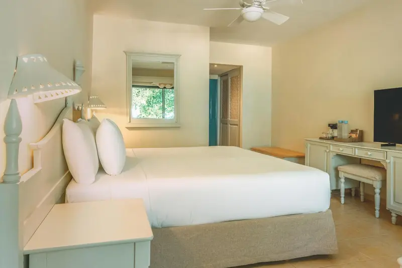 Une chambre lumineuse avec un grand lit recouvert de blanc.