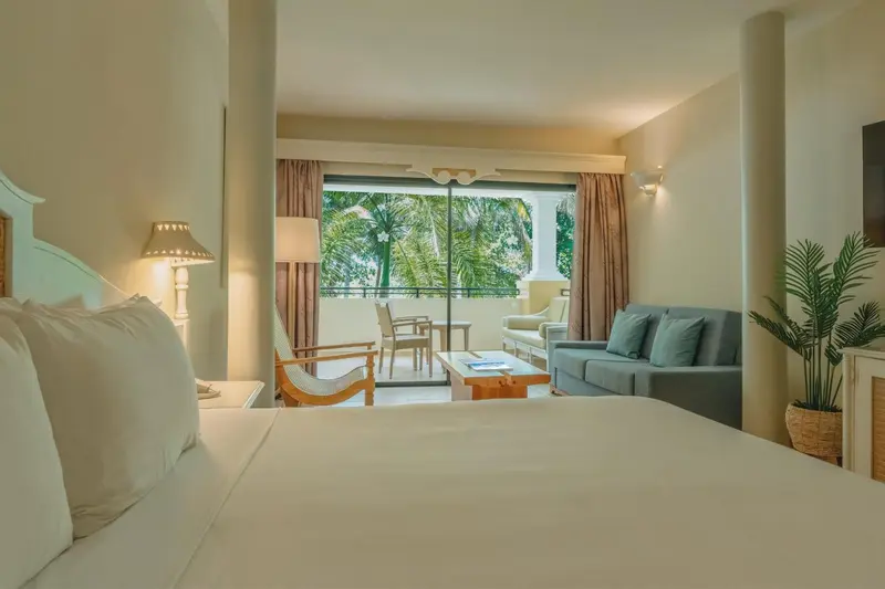Une chambre lumineuse s'ouvre sur une terrasse avec vue sur la végétation.