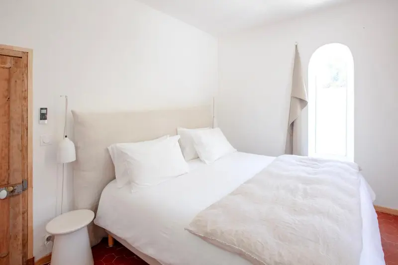 Une chambre lumineuse avec un grand lit recouvert de linge blanc.
