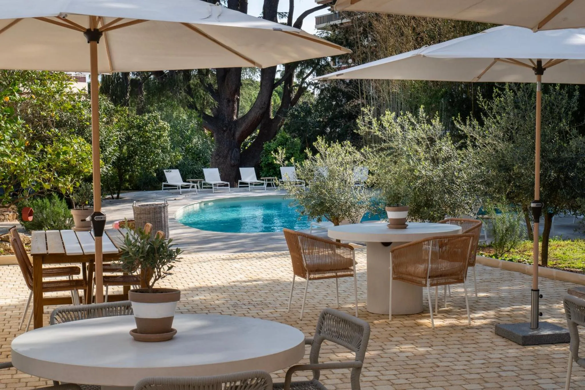 Terrasse aménagée avec tables et chaises près d'une piscine.