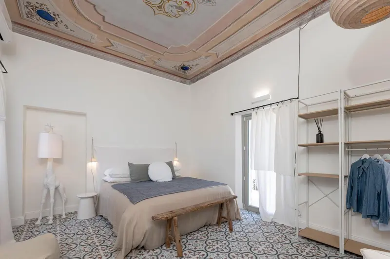 Une chambre lumineuse avec un lit double et un sol carrelé.