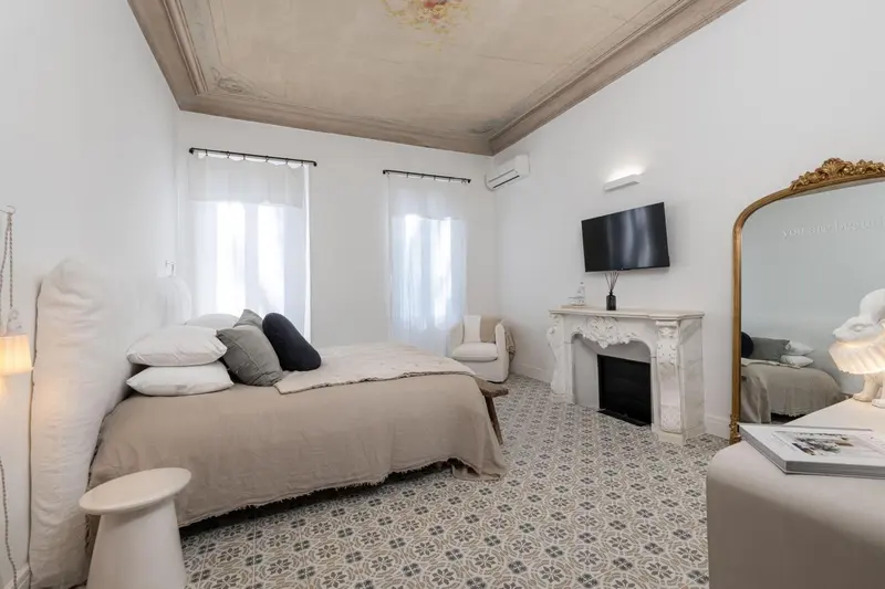 Une chambre lumineuse avec un lit double et un téléviseur mural.