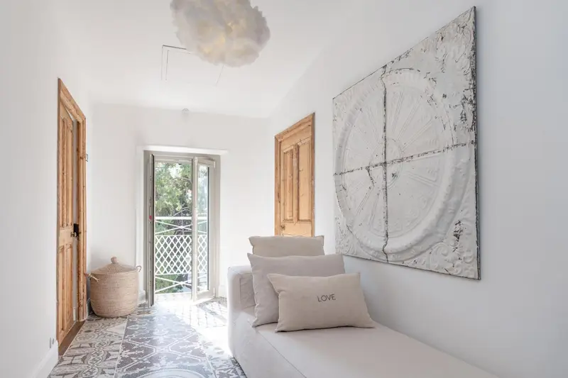 Un espace de détente lumineux avec un canapé blanc et un tableau décoratif.