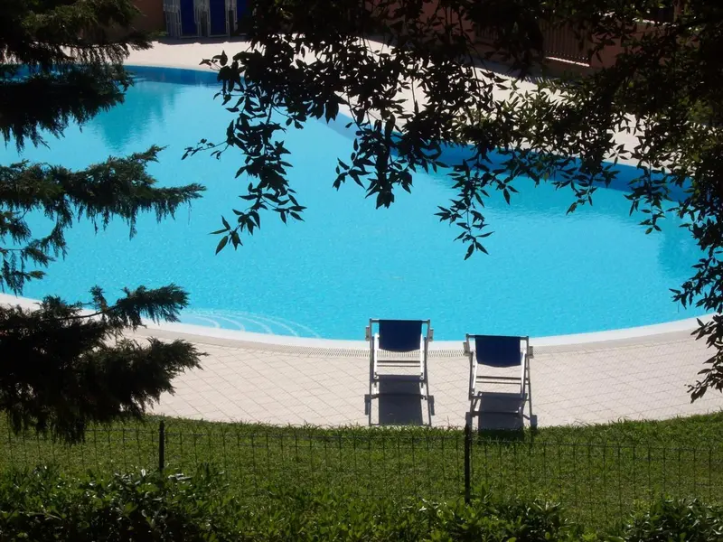 Deux transats bleus sont placés au bord d'une piscine turquoise entourée d'une terrasse.