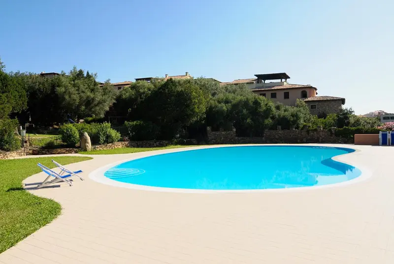 Une piscine rectangulaire avec un sol carrelé et des transats bleus.