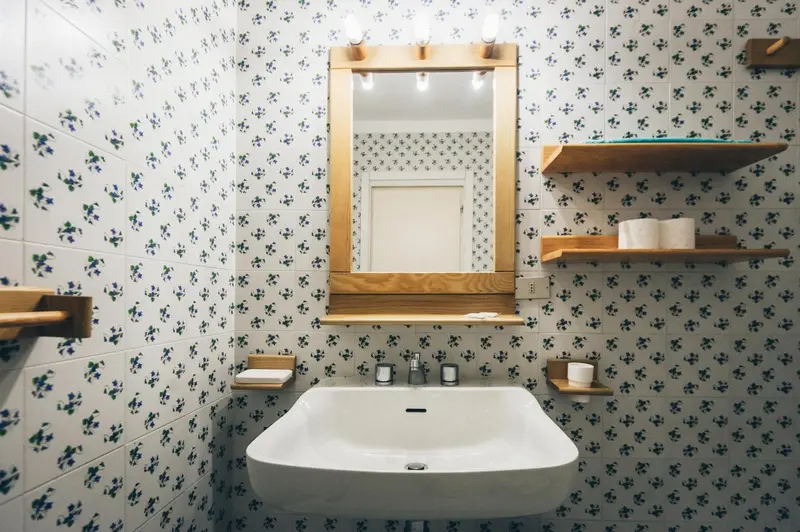 Une salle de bain avec un lavabo mural et un miroir décoratif.