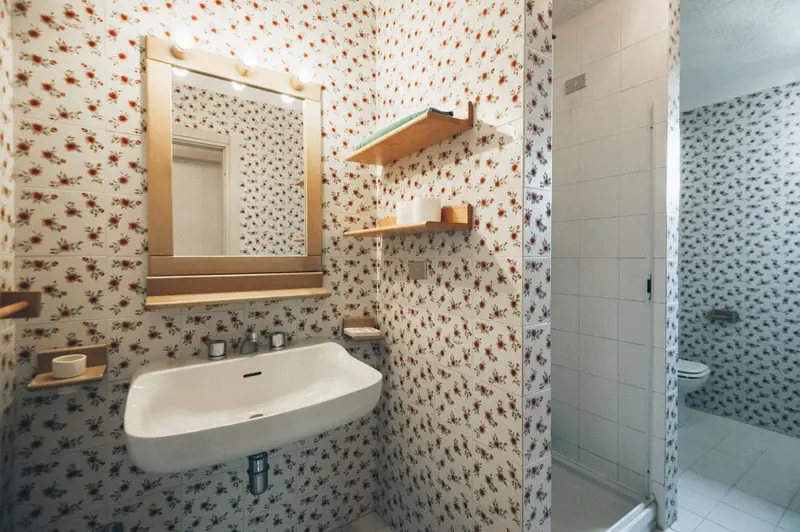 Une salle de bain carrelée avec un lavabo et un miroir.