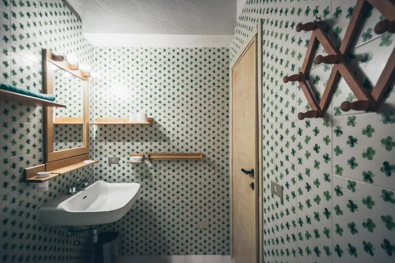 Une salle de bain carrelée avec un lavabo et un porte-serviettes en bois.