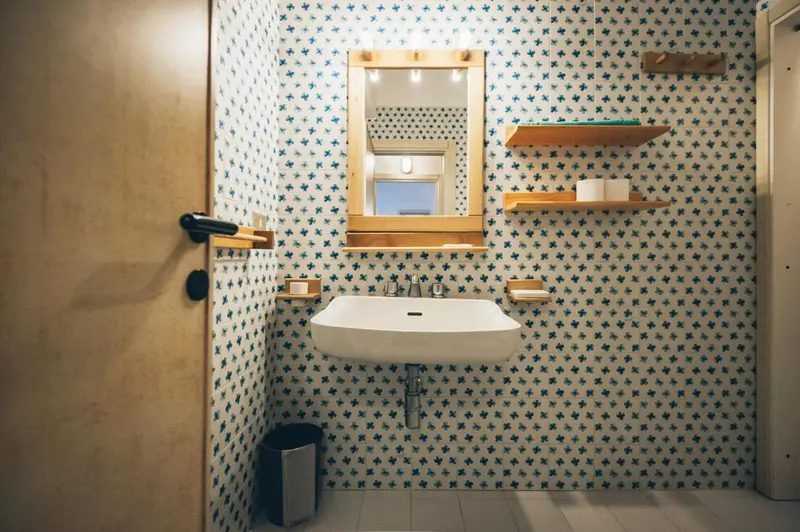 Une salle de bain avec un lavabo mural et un miroir éclairé.