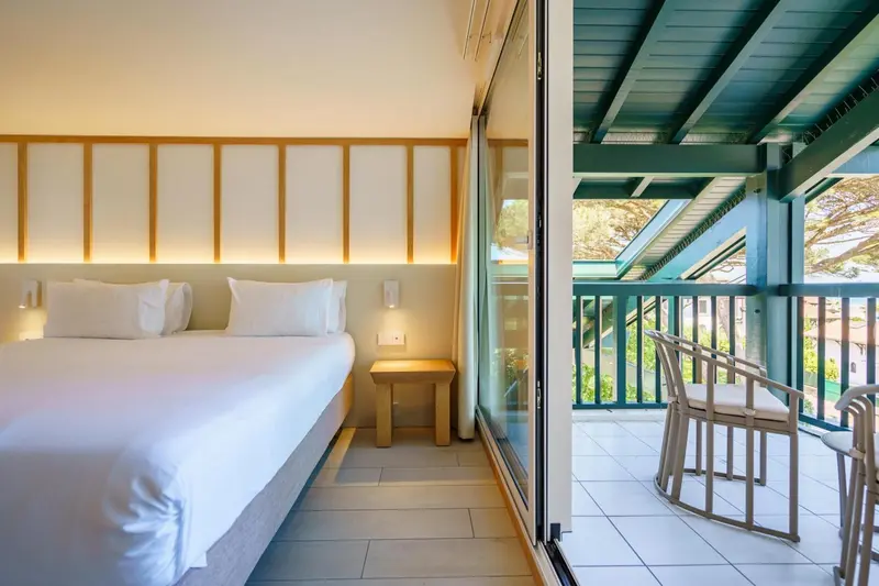 Une chambre lumineuse s'ouvre sur une terrasse avec mobilier.