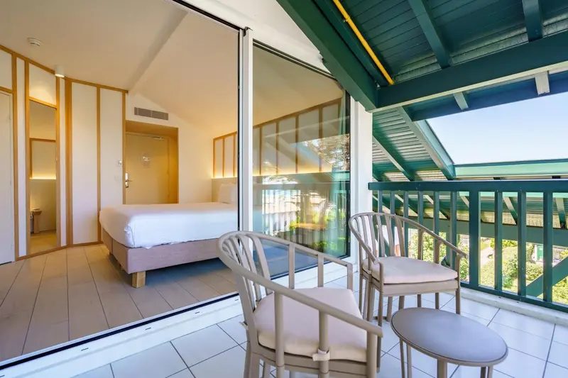 Une chambre lumineuse s'ouvre sur une terrasse avec mobilier d'extérieur.