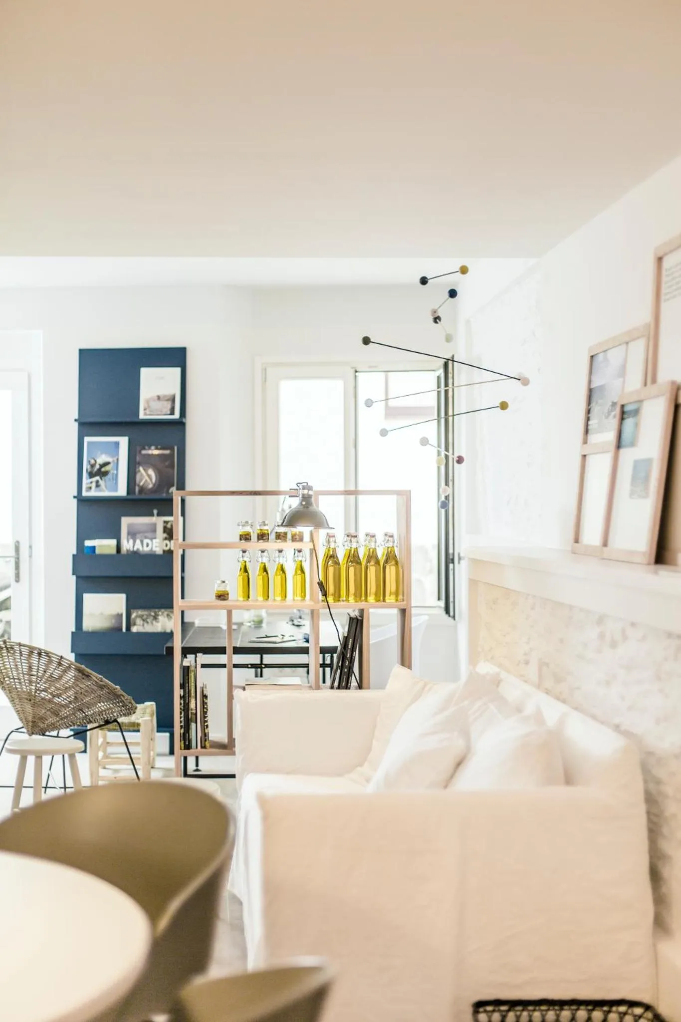 Un canapé blanc et une étagère sombre dominent une pièce lumineuse.
