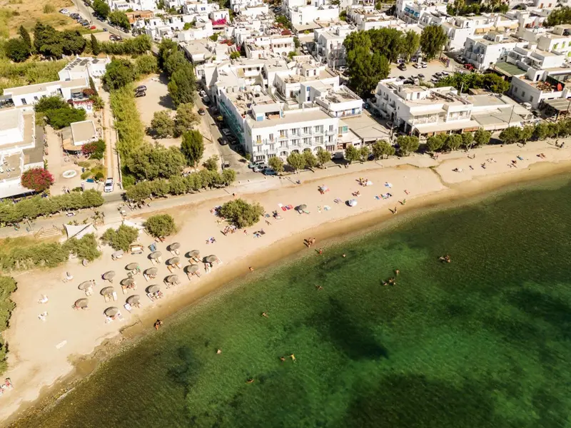 Vue aérienne d'une plage bordée de bâtiments blancs et de parasols.