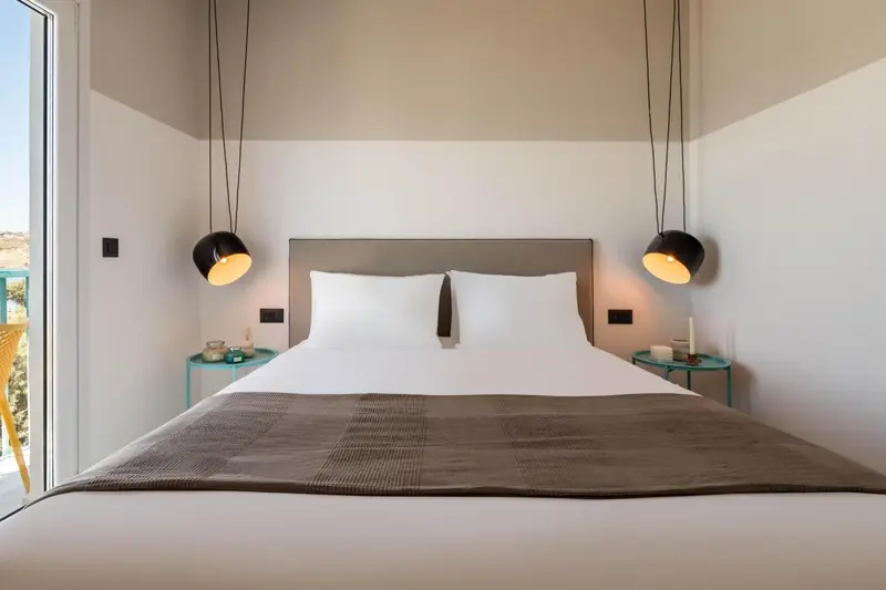 Une chambre lumineuse avec un grand lit et des lampes suspendues.