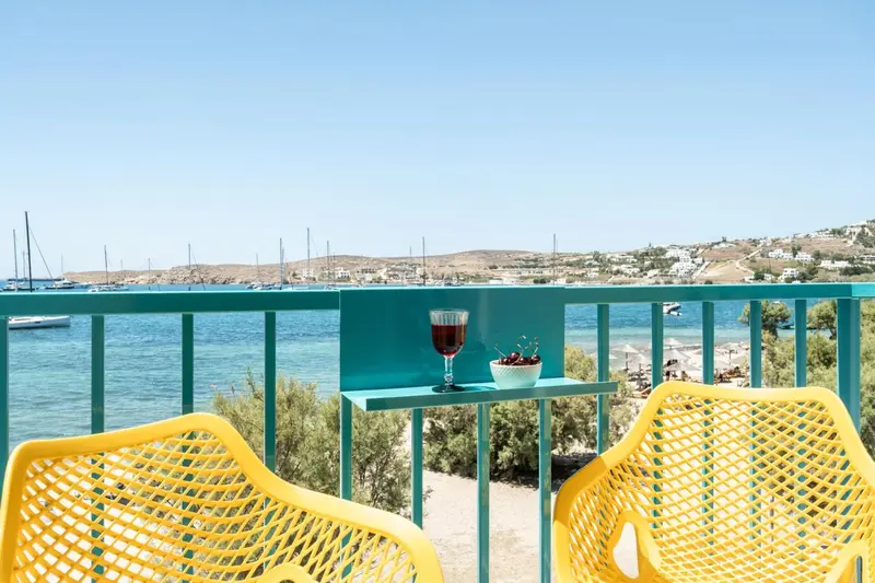 Deux chaises jaunes et une table turquoise offrent une vue sur la mer et le littoral.