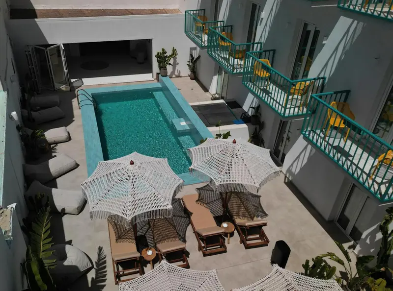 Vue aérienne d'une piscine entourée de transats et de parasols.