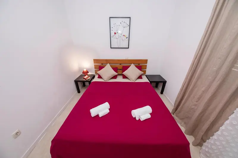 Une chambre avec un grand lit recouvert d'une courtepointe rouge et de deux oreillers.