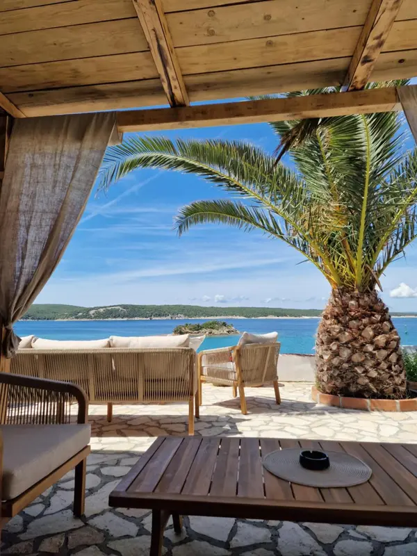 Espace de détente extérieur avec mobilier en rotin et vue sur la mer.
