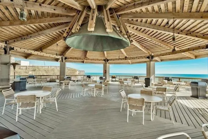 Terrasse en bois abritée avec tables et chaises face à la mer.