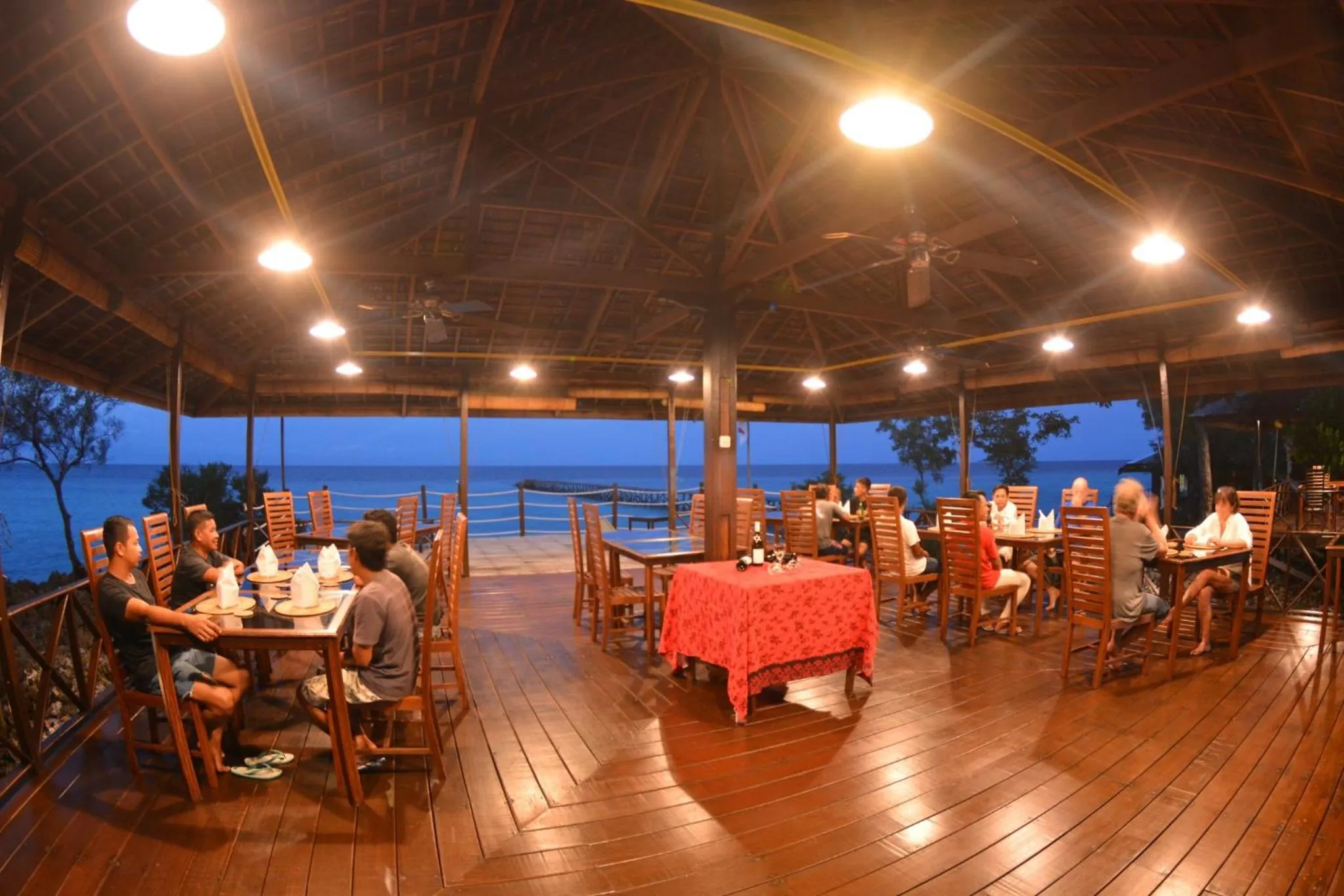 Des convives sont attablés dans un restaurant en plein air avec vue sur la mer.