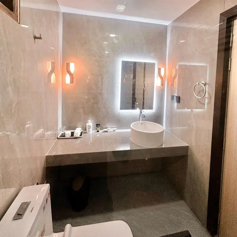 Une salle de bain moderne avec un grand miroir éclairé et un lavabo intégré.
