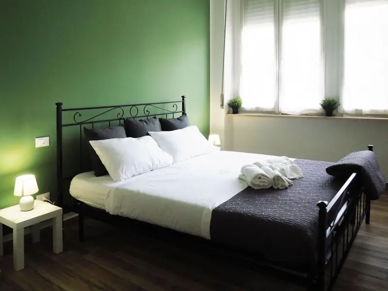 Une chambre avec un grand lit recouvert d'une couette sombre et de plusieurs oreillers.