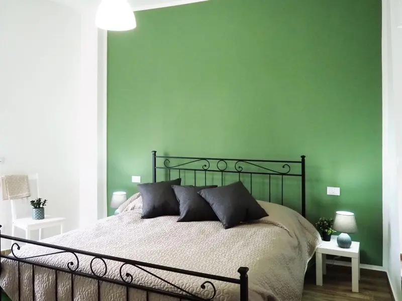 Une chambre avec un lit recouvert d'une couverture claire et de coussins foncés.
