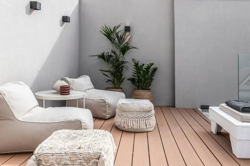 Espace de détente extérieur avec mobilier blanc et plantes vertes.