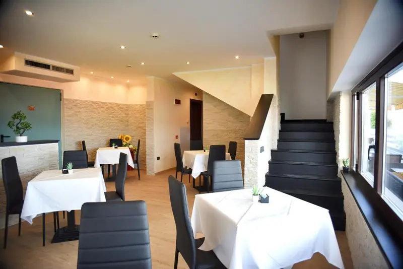 Une salle lumineuse avec des tables nappées et un escalier noir.