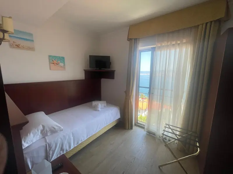 Une chambre lumineuse avec un lit simple et une vue sur la mer.