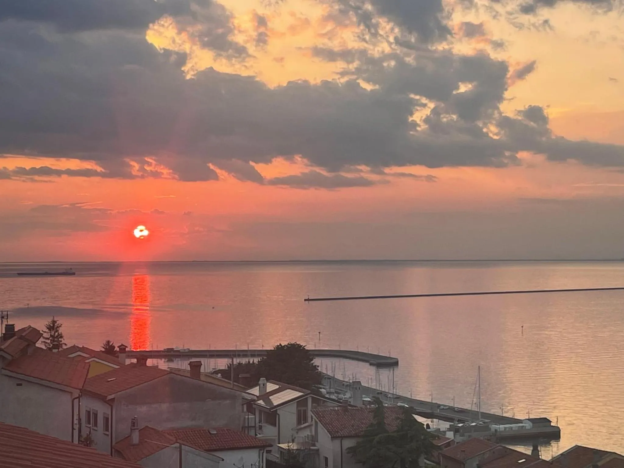 Coucher de soleil sur la mer avec des toits en premier plan.