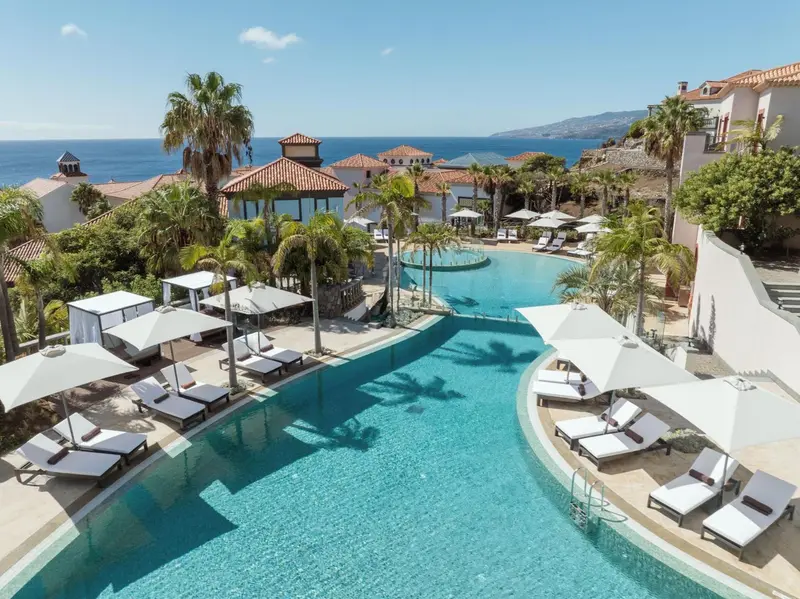 Vue aérienne d'une piscine d'hôtel avec des transats et des parasols.