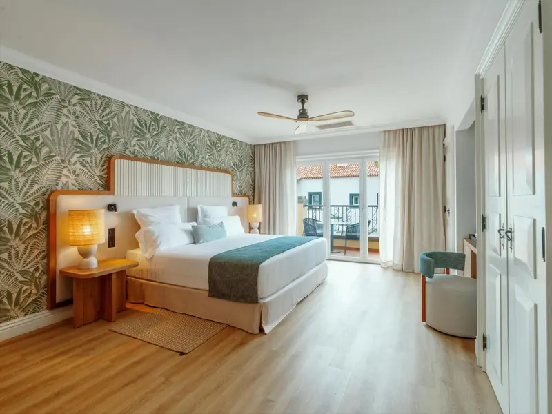 Une chambre lumineuse avec un grand lit et un accès à un balcon.