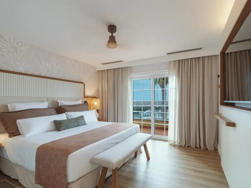 Une chambre lumineuse avec un grand lit et un accès à une terrasse.