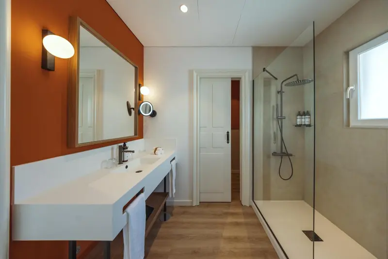 Une salle de bain moderne avec douche à l'italienne et grand miroir.