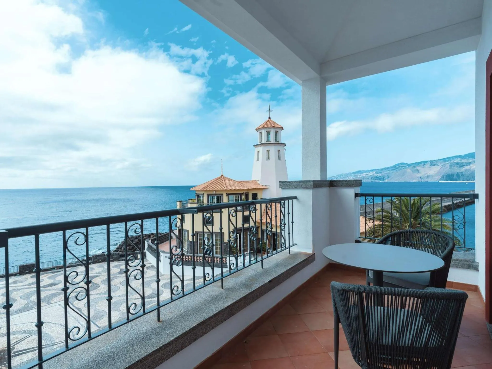 Terrasse avec mobilier d'extérieur donnant sur une vue mer et un paysage montagneux.