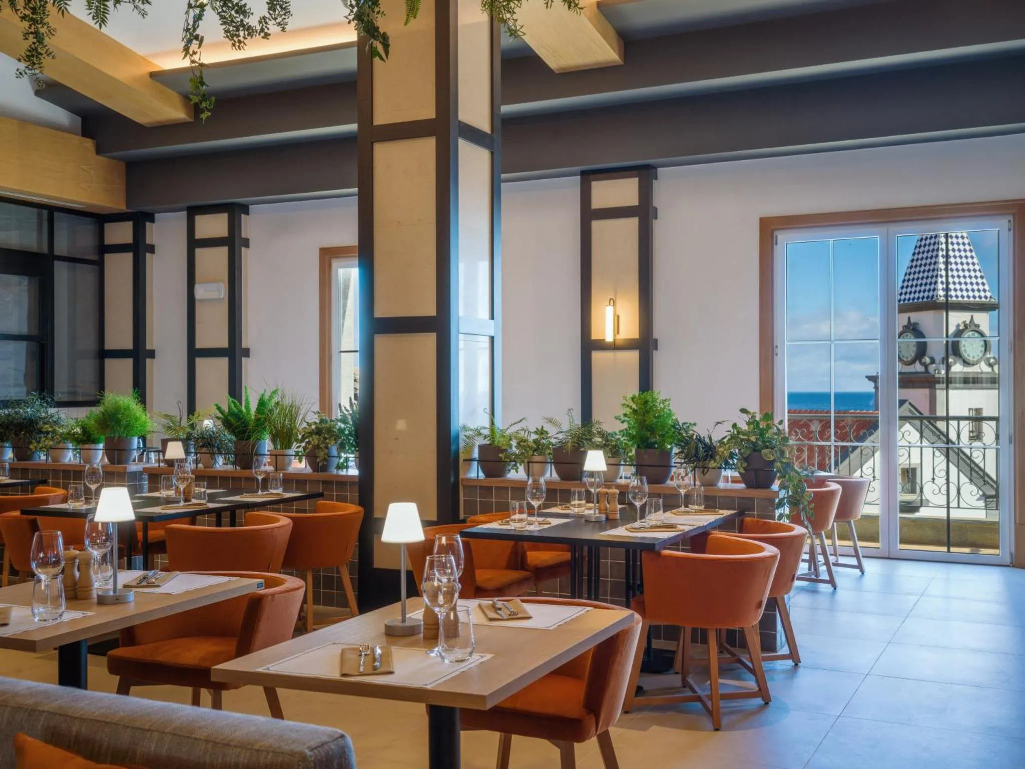 Une salle de restaurant lumineuse avec des tables dressées et une vue sur la mer.