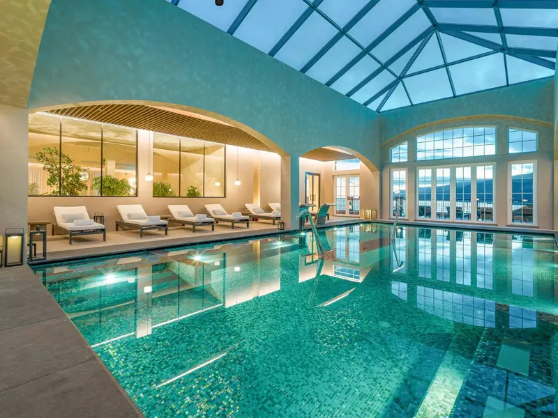 Une piscine intérieure lumineuse avec des chaises longues et de grandes fenêtres.