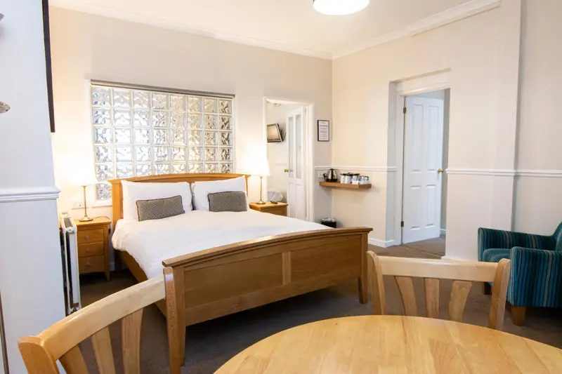 Une chambre lumineuse avec un lit double et un coin repas.