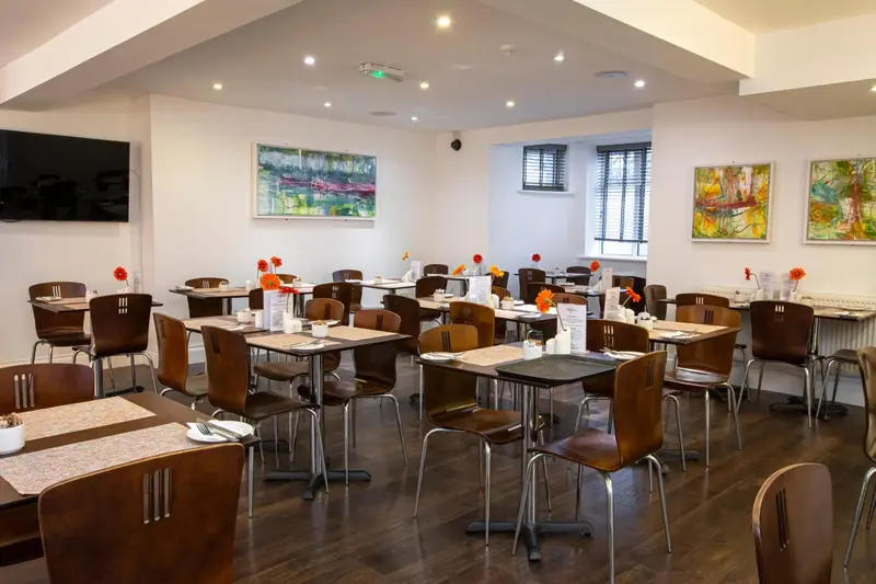 Une salle lumineuse avec des tables dressées pour le repas.