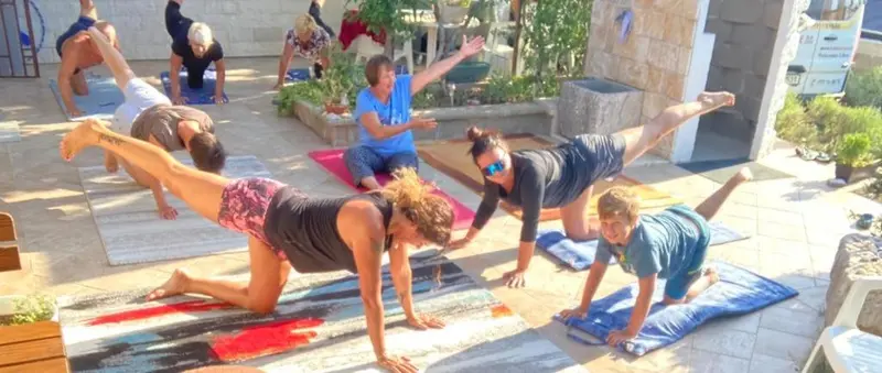 Des personnes pratiquent le yoga sur des tapis dans une cour ensoleillée.