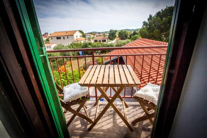 Une terrasse avec une table et des chaises offre une vue sur les toits et la végétation.